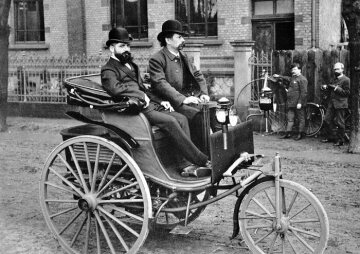 The Patent Motor Car of 1887, an advanced version of the first motor car of 1886. At the wheel: Carl Benz, with his commercial clerk Josef Brecht beside him.