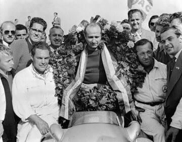 Dutch Grand Prix in Zandvoort on 19 June 1955. Winner Juan Manuel Fangio (in a Mercedes-Benz W 196 R with start number 8) with laurel wreath and mechanics Erwin Grupp and Hermann Eger (left).